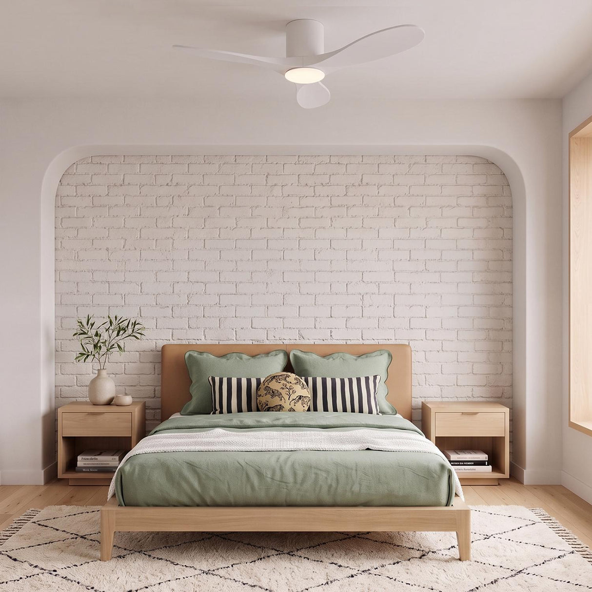 A modern bedroom featuring the Eider LED Ceiling Fan 44", Matte White Oak along the ceiling center over a wood bed with sage green linens and white brick.