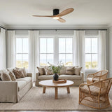 A coastal living room with the Eider LED Ceiling Fan 52", Natural Oak and Matte Black mounted to the ceiling above rattan armchairs and neutral sofas.