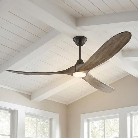 A modern farmhouse living room with the Egret LED Ceiling Fan in gray wash oak and aged pewter finish on a white beamed ceiling above bright windows.