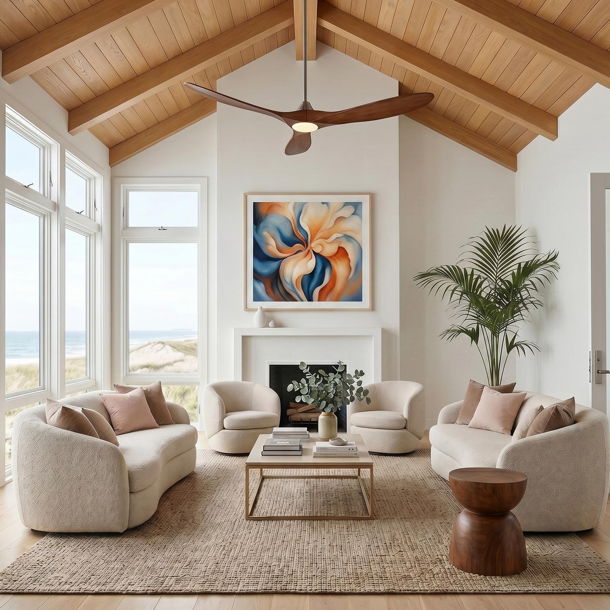 A coastal living room features an Egret LED Ceiling Fan 70" in koa wood and brushed steel installed on a vaulted ceiling above white boucle sofas.