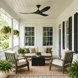A traditional white siding porch featuring the Egret Outdoor Ceiling Fan 52", Matte Black mounted on a beadboard ceiling above green lounge furniture and black shutters.
