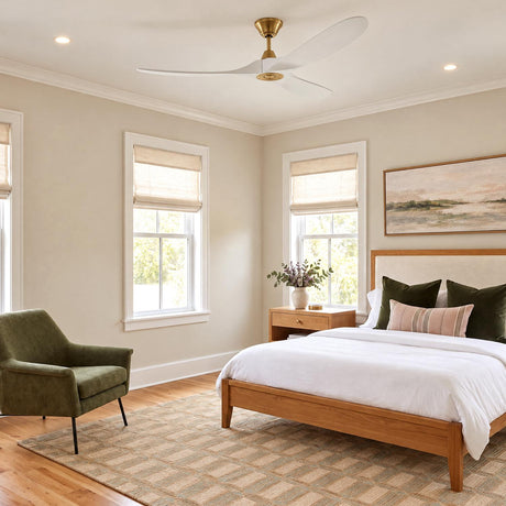 A transitional bedroom features the Egret Ceiling Fan 60", Matte White Oak and Modern Brass mounted on the ceiling above a wood bed and green armchair.