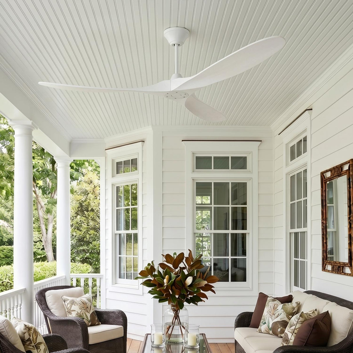 A modern farmhouse porch with the Egret Ceiling Fan 70" Matte White Oak in a matte white oak finish on a beadboard ceiling above dark wicker furniture.