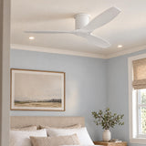 A coastal bedroom features a matte white ceiling fan centered above a beige upholstered headboard, light blue walls, and a woven window shade.
