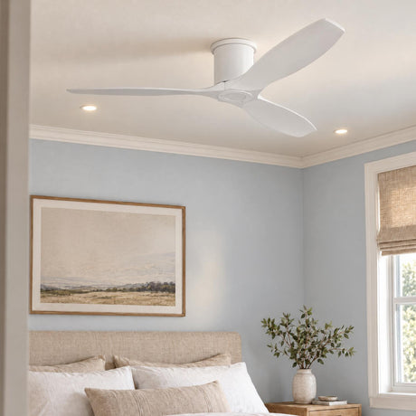 A coastal bedroom features a matte white ceiling fan centered above a beige upholstered headboard, light blue walls, and a woven window shade.