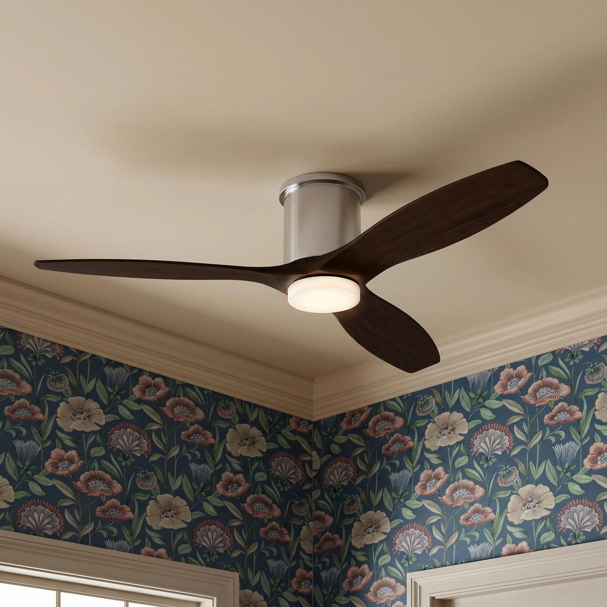 A transitional bedroom featuring the Harrier LED Smart Ceiling Fan 52", Walnut Wood and Brushed Steel, on a standard ceiling beside blue floral wallpaper and cream crown molding.