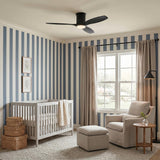 A transitional nursery with blue and white striped wallpaper features the Harrier LED Smart Ceiling Fan 52 in matte black oak mounted above a light gray crib.