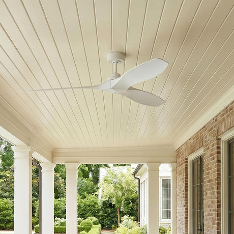 A traditional home porch with the Heron Outdoor Smart Ceiling Fan 60", Matte White on a shiplap ceiling beside a red brick wall, white columns, and boxwood hedges.