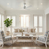 A coastal living room featuring the Sora Ceiling Fan 44", Matte White mounted on a white shiplap ceiling above a white sofa and a fiddle leaf fig.