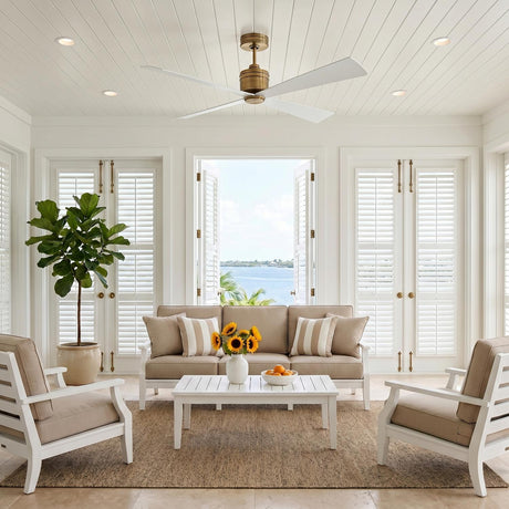 A coastal living room with a Sora Ceiling Fan 56", Antique Rubbed Brass and Matte White along the white shiplap ceiling over a tan sofa and jute rug.