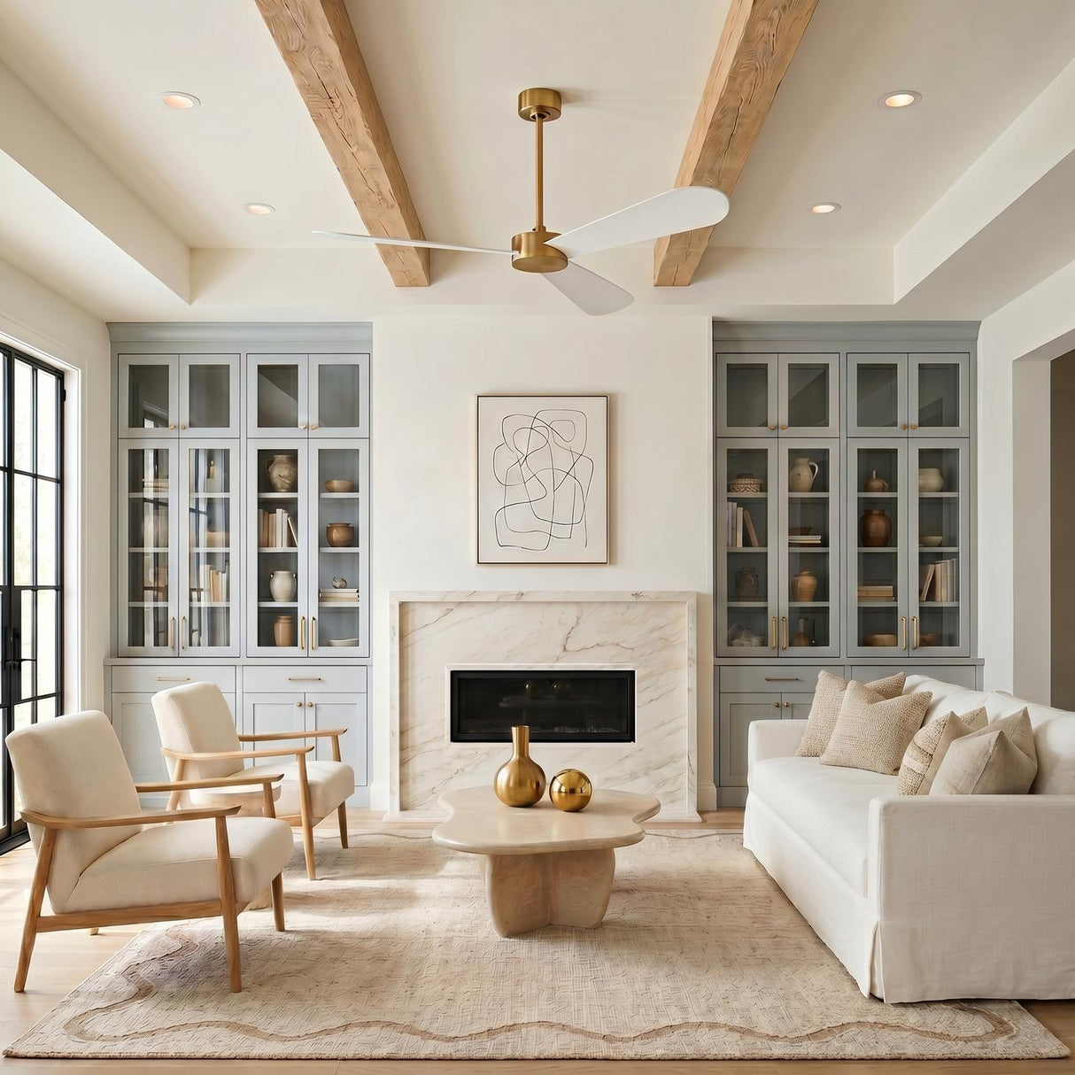A transitional living room with the Willet Smart Ceiling Fan 60", Modern Brass and Matte White mounted to a beamed ceiling above a marble fireplace.