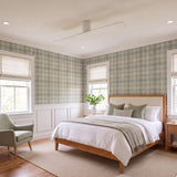 A transitional bedroom featuring the Finch Smart Ceiling Fan 60 in matte white oak centered on the ceiling above a wooden bed frame and plaid wallpaper.