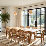 A transitional dining room featuring the Thornton Linear Pendant 60 inch in gold leaf over a wood table with cane chairs and black framed doors.