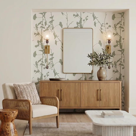 A contemporary living room with two Lockwood Wall Sconce 33 inch fixtures in vintage brass and frosted glass flanking a mirror above a wood sideboard with botanical wallpaper.
