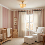 A traditional bedroom with the Cortland Semi-Flush in champagne glass and distressed bronze at the ceiling center, featuring pink striped wallpaper and a light wood crib.