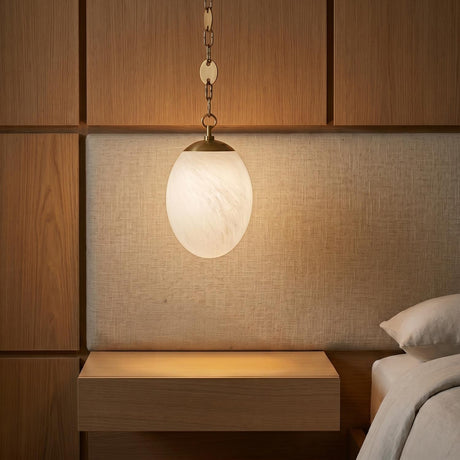 A modern bedroom featuring the Kelton Small Pendant 8", Cloud Glass and Aged Brass hanging over a floating wood nightstand beside a linen textured headboard.