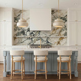 A transitional kitchen with two Ellsworth Pendants in taupe crackle ceramic and aged brass over a white island featuring a dramatic marble backsplash and light blue cabinetry.