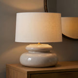 A transitional foyer with the Ellsworth Table Lamp 20", Taupe Crackle Ceramic on a light wood console table beside a round bronze framed mirror.