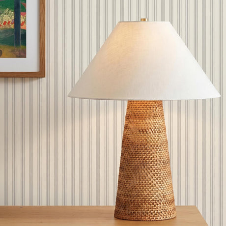 A coastal living room with the Arly Table Lamp 26", Natural Rattan featuring a white linen shade on a wood console table against pinstripe wallpaper.