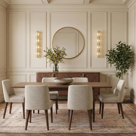 A transitional dining room with two aged brass and clear piastra glass wall sconces flanking a round mirror above a walnut sideboard and coffered ceiling.