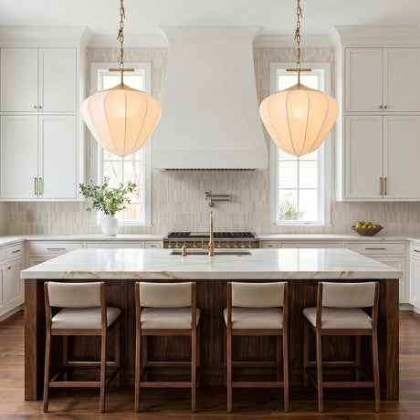 A transitional kitchen with two vintage brass and white silk pendants hanging over a white marble island with dark wood base and vertical tile backsplash.