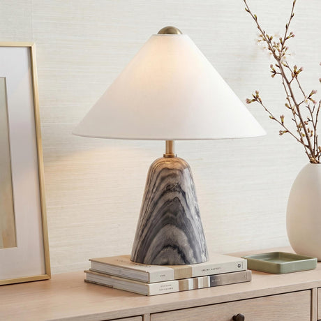 A transitional living room featuring a Hendrix Table Lamp 19 with a gray marble base and white linen shade atop a light wood console table.