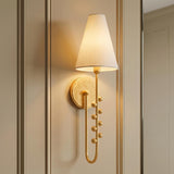 A traditional foyer with the Linnea Wall Sconce in a gold leaf finish featuring a white linen shade and beaded detailing on beige wall paneling.