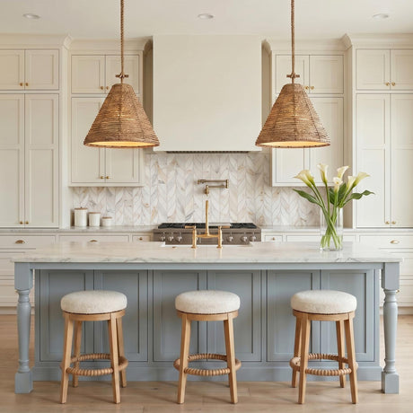 A farmhouse kitchen with two braided jute and patina brass pendants over a white marble island featuring blue shaker cabinetry and a chevron marble tile backsplash.