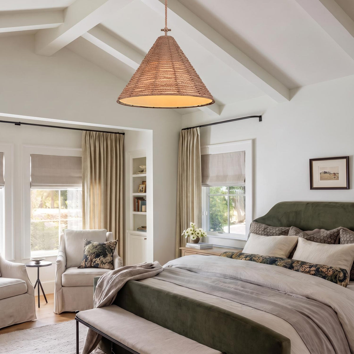 A modern farmhouse bedroom with a braided jute and patina brass cone pendant suspended from a vaulted beamed ceiling over a green velvet upholstered bed.