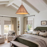A modern farmhouse bedroom with a braided jute and patina brass cone pendant suspended from a vaulted beamed ceiling over a green velvet upholstered bed.