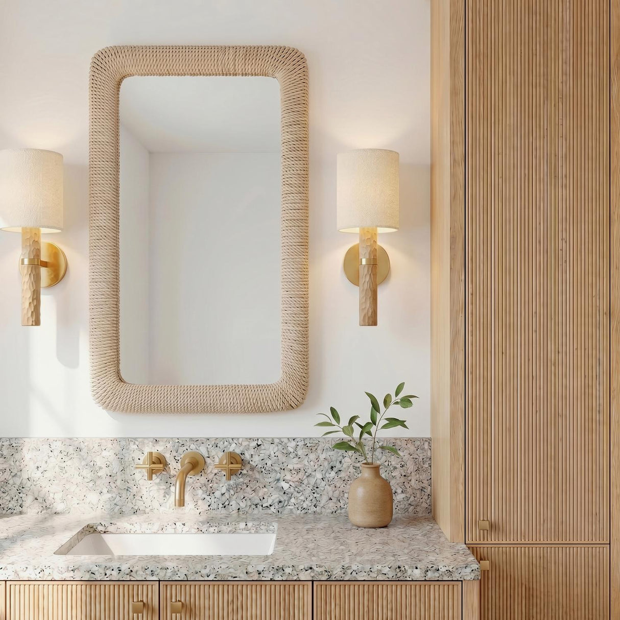 A coastal bathroom with two Gillian Wall Sconces featuring ivory boucle shades and beech wood bases flanking a rope-wrapped mirror above a terrazzo countertop.