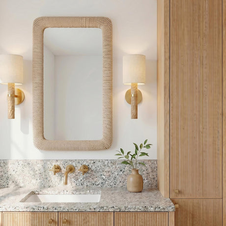 A coastal bathroom with two Gillian Wall Sconces featuring ivory boucle shades and beech wood bases flanking a rope-wrapped mirror above a terrazzo countertop.