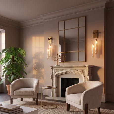 A Mediterranean living room with Florencea LED wall sconces in vintage brass and champagne glass flanking a mirror above an ornate stone fireplace and boucle chairs.