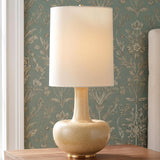 A traditional bedroom featuring the Viviana Table Lamp 28", Biscotti Glaze with a white linen drum shade on a wood nightstand beside green floral wallpaper.