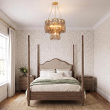 A traditional bedroom featuring the Petronella gold leaf and smoke taupe swirled glass chandelier centered over a dark wood four-poster bed against floral patterned wallpaper.