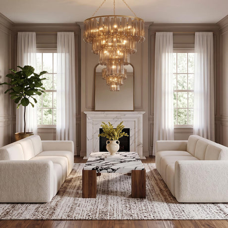 A transitional living room features the Petronella Four-Tier Chandelier with gold leaf and smoke taupe swirled glass above a marble coffee table flanked by cream sofas.