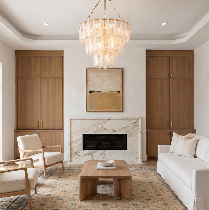 A contemporary living room with the Courtney Three-Tier Chandelier 34 inch in gold leaf and piastra glass over a wood coffee table and marble fireplace surround.