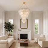 A transitional living room featuring a gold leaf and piastra glass chandelier suspended over a marble fireplace, walnut coffee table, and cream boucle furniture.