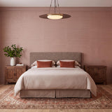A contemporary bedroom featuring the Colburn Extra Large LED Pendant 40 inch in Vintage Bronze centered over a bed with pink grasscloth walls and wood bedside cabinets.