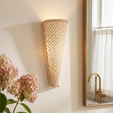 A coastal bathroom features the Dalmar LED Wall Sconce 16", Ivory Beaded mounted at the vanity beside a brass framed mirror and pink hydrangeas.