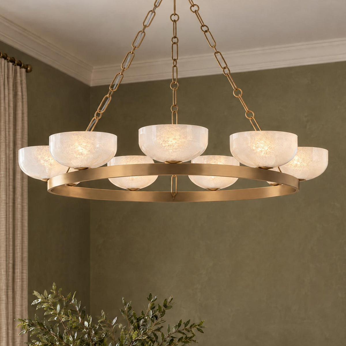 A transitional dining room featuring the Halcyon 9 Light Chandelier 44-inch in patina brass with seeded cloud glass shades against olive green walls and neutral drapes.