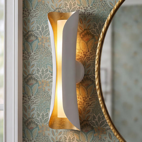 A transitional bathroom with the white and gold leaf Rhys Wall Sconce 21" mounted on botanical floral wallpaper beside a hammered gold round mirror.