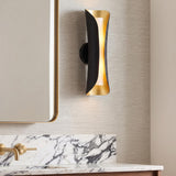 A contemporary bathroom featuring the Rhys Wall Sconce 21", Matte Black and Gold Leaf mounted beside a gold-framed mirror above a white marble vanity backsplash.