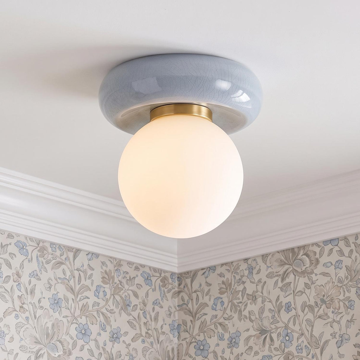 A traditional foyer with the Coburn Flush Mount in light blue crackle and opal glass mounted to a ceiling with white crown molding and floral wallpaper.