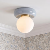 A traditional foyer with the Coburn Flush Mount in light blue crackle and opal glass mounted to a ceiling with white crown molding and floral wallpaper.