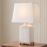 A transitional living room with the Hallie Table Lamp 17 inch, White Glaze with White Shade on a walnut side table against beige striped wallpaper.