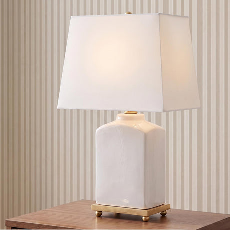 A transitional living room with the Hallie Table Lamp 17 inch, White Glaze with White Shade on a walnut side table against beige striped wallpaper.