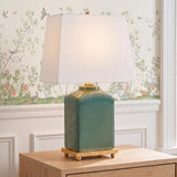 A traditional living room featuring the Hallie Table Lamp 17 inch Jade Glaze with White Shade on a natural wood side table against floral bird wallpaper.