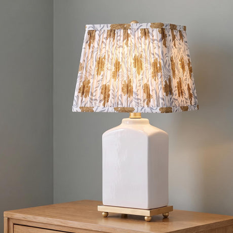 A traditional bedroom with the Hallie Table Lamp 17", White Glaze with Bloom Printed Shade on a light wood nightstand in front of gray walls.