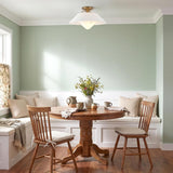 A transitional dining nook with sage green walls features the Rey Large Semi-Flush Mount 21", White and Patina Brass over a round wood dining table.